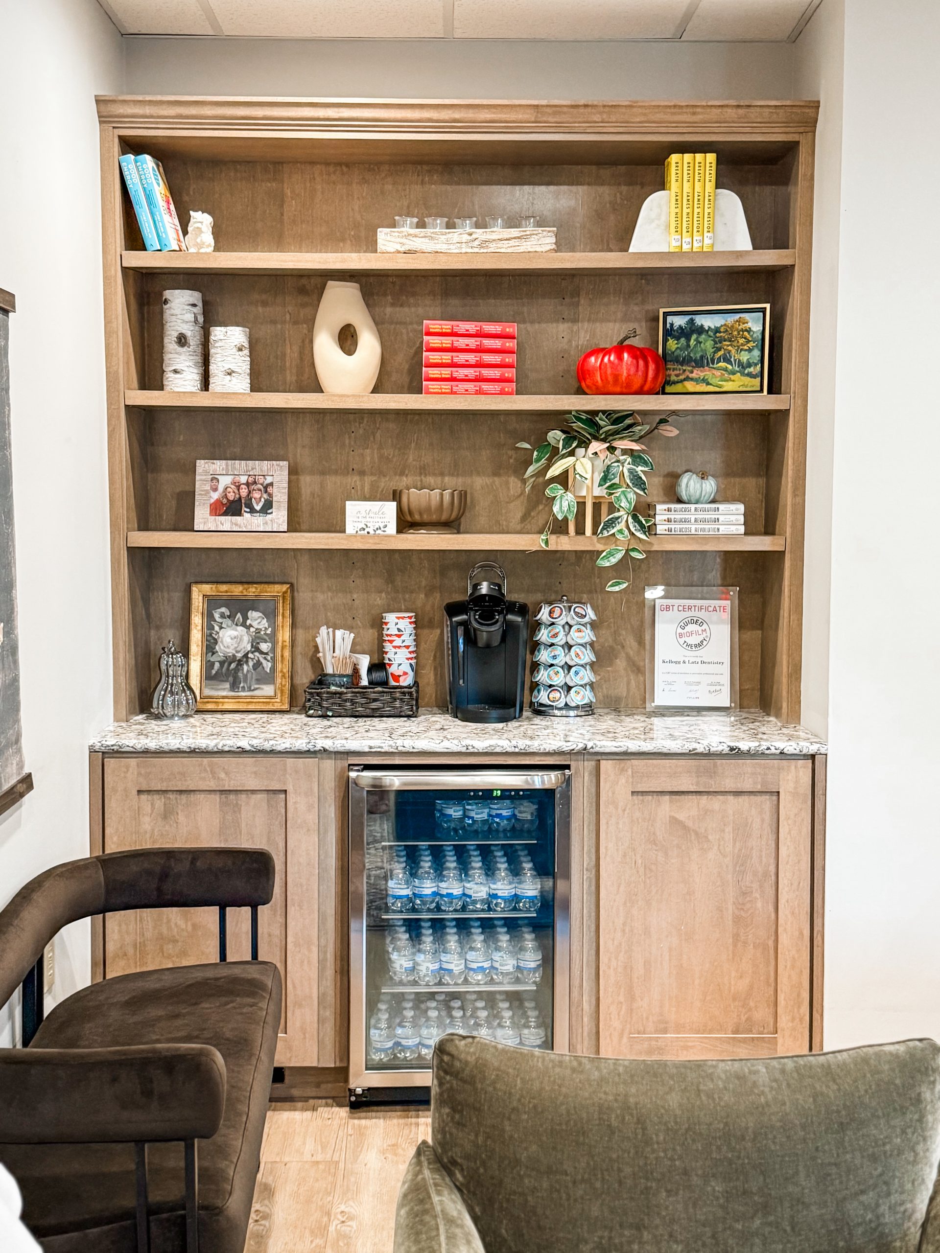 Waiting and break room with chairs, a fully stocked water fridge, and a bookshelf, showing a comfortable and welcoming break room area.